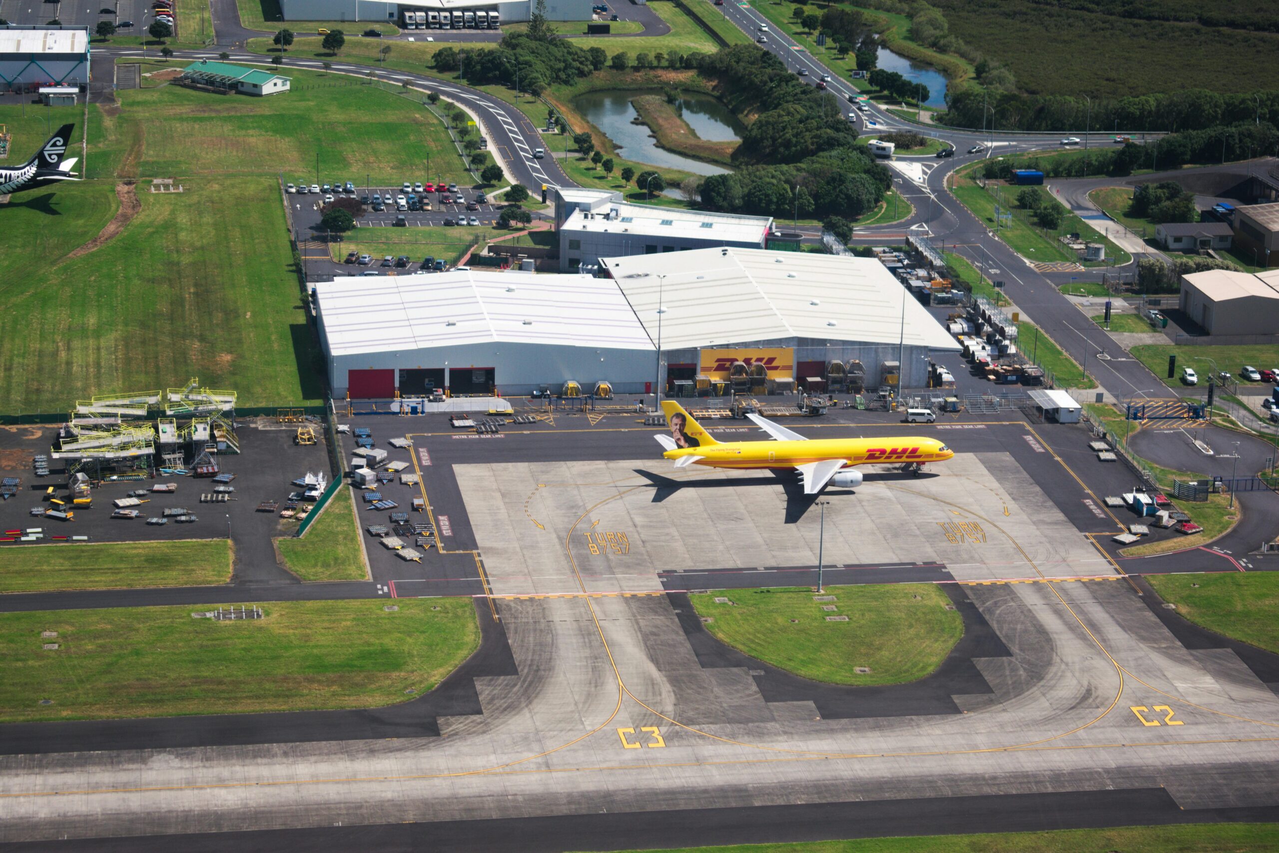pexels-photo-12545493-12545493 Aerial photo showcasing DHL airplane and hangar facilities in a busy airport setting.