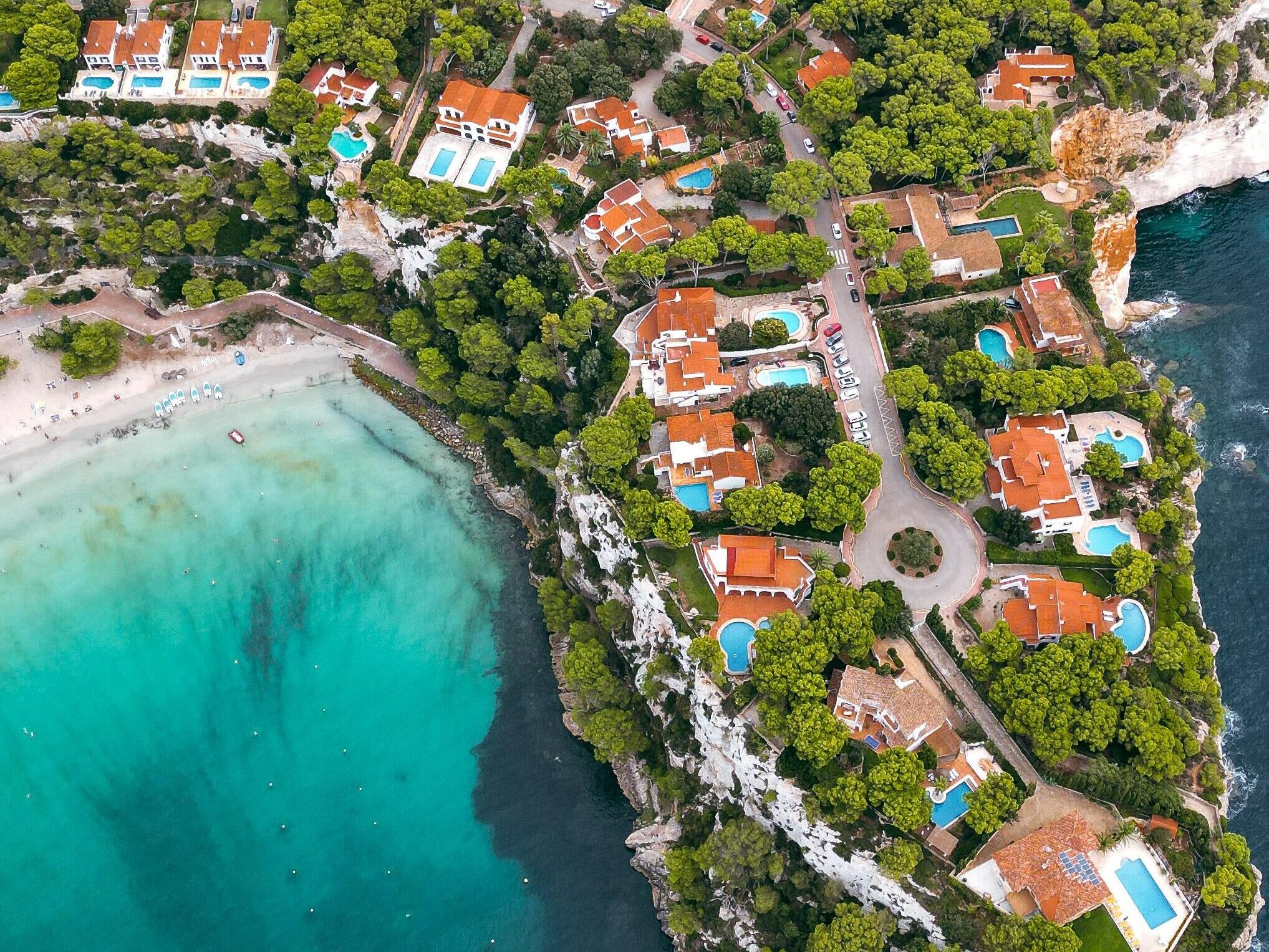 Explore the breathtaking aerial view of Cala Galdana, showcasing its turquoise waters and lush greenery.