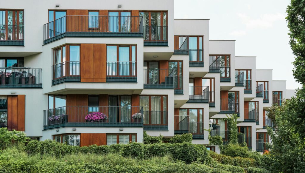Modern residential building with glass balconies and lush greenery.