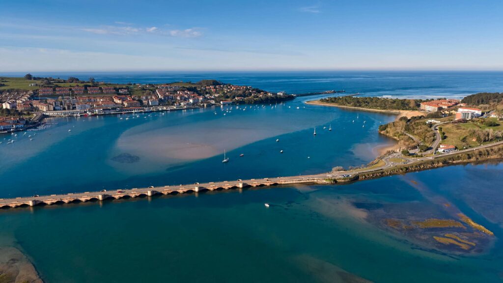 pexels-photo-36732247-36732247 Scenic aerial view of Cantabria's coastline with a bridge spanning the blue waters and a vibrant town.