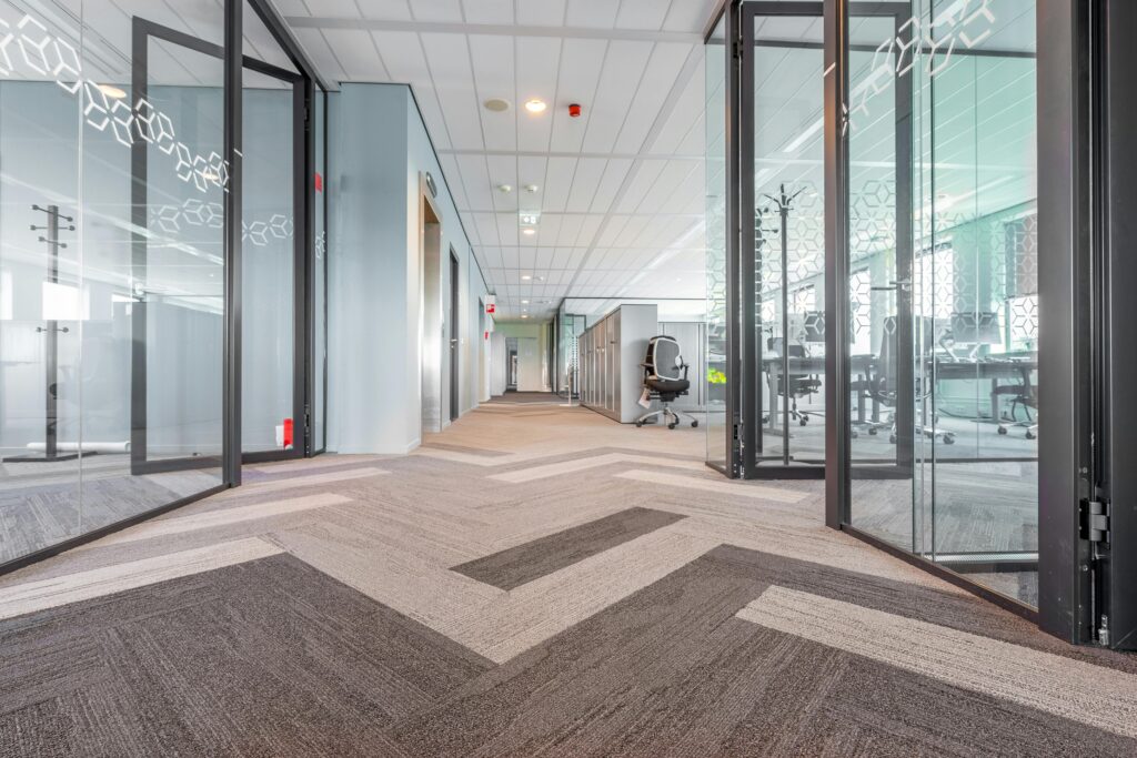 Spacious and bright modern office hallway with glass partitions and contemporary design.