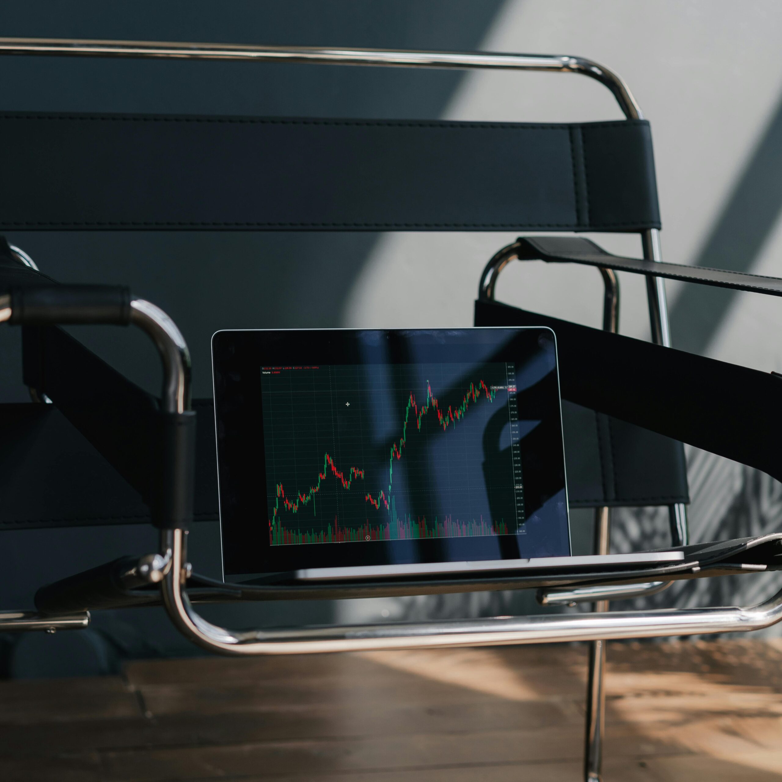 An empty designer chair with a tablet showing a stock market graph, creating a modern business atmosphere.