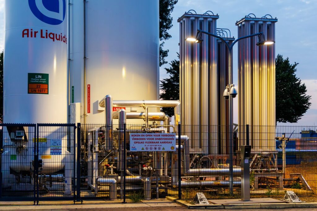 Illuminated industrial gas facility in Rotterdam, showcasing equipment and tanks against a twilight backdrop.